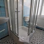 Badezimmer mit Dusche, Waschbecken und Toilette. Fliesenboden und blaue Wände.