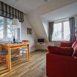 Wohn- und Essbereich mit rotem Sofa, Holztisch und Fenstern.