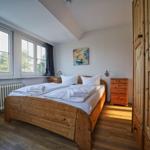 Schlafzimmer mit Holzbett, Fenster und Kleiderschrank.