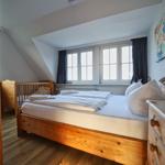 Schlafzimmer mit Holzbett, Kinderbett und Fenster.