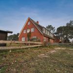 Rotes Backsteinhaus mit Holzzaun und Bäumen im Hintergrund.