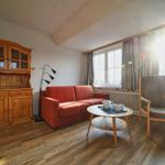 Wohnzimmer mit rotem Sofa, Holzmöbeln und Fenster mit Blick.