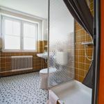 Bad mit Dusche, Toilette und Waschbecken. Fliesen und Fenster sichtbar.