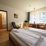 Zwei Betten, Tisch mit Stühlen, Fenster mit Blick, Holzboden und Tür zum Bad.