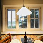 Esszimmer mit Tisch, Stühlen und Fensterblick auf Feld und Bäume.