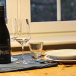 Tisch mit Weinflasche, Gläsern und Geschirr vor Fenster