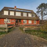 Rotes Backsteinhaus mit Holzumzäunung und Solaranlage auf Dach