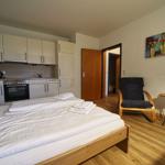 Schlafzimmer mit Bett, Küchenzeile und Sessel.