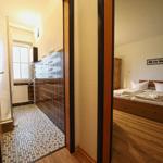 Schlafzimmer mit Holzbett und Badezimmer mit Mosaikfliesen