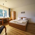 Schlafzimmer mit Bett, Tisch, Stühlen und Küchenzeile.