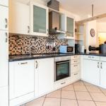 Küche mit weißen Schränken, Mosaikwand und Edelstahlgeräten.