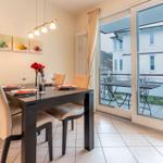 Esszimmer mit Tisch, Stühlen und Balkonansicht.