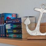 Ein silbernes Ankerobjekt steht auf einem Holzregal neben Büchern.