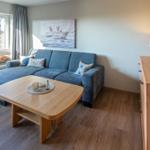 Wohnzimmer mit Sofa, Tisch und Fensterblick auf Garten