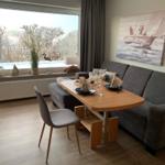 Essbereich mit Tisch, Stuhl und Sofa. Große Fensterfront mit Blick auf Garten.