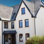 Ferienhaus mit weißer Fassade und grauem Dach. Eingang unter Vordach.