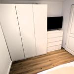 Schlafzimmer mit weißen Schränken, TV und Holzboden