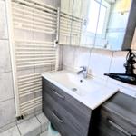 Bad mit Waschbecken, Spiegel und Heizkörper an der Wand.