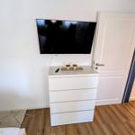 Schlafzimmer mit Fernseher, Schrank und Tür zum Flur.