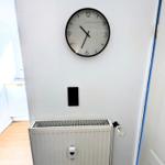 Wanduhr über Heizkörper an weißer Wand in Flur