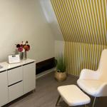 Room with white armchair, cabinet, and striped wall