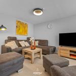 Wohnzimmer mit Sofa, Couchtisch und Fernseher auf Holzkonsole.