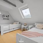 Zimmer mit zwei Betten, Dachschräge und Dachfenster. Wandbild mit Mickey Mouse.