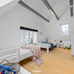 Zimmer mit zwei Betten, Holzboden und Dachschrägen mit Balken.
