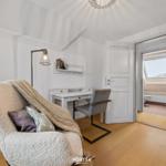 Schlafzimmer mit Schreibtisch, Sessel und Blick in Badezimmer.