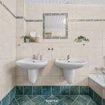 Badezimmer mit zwei Waschbecken, Badewanne und Heizkörper.
