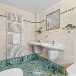 Badezimmer mit zwei Waschbecken, Dusche und Heizkörper