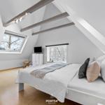 Schlafzimmer mit Dachschrägen, Fenster und Bett.