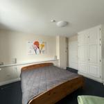 Schlafzimmer mit Holzbett, weißer Schrank und Wandbild.