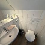 Badezimmer mit Waschbecken, Spiegel, Toilette und WC-Bedienung.