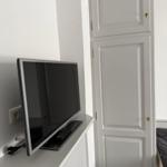 TV auf weißen Möbeln neben weißer Schrankwand