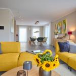 Wohn- und Essbereich mit gelben Sofas, Sonnenblumen und moderner Einrichtung.