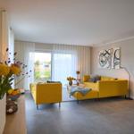 Wohnzimmer mit gelben Sitzgelegenheiten, großen Fenstern und moderner Einrichtung.