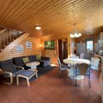 Wohnbereich mit Sofa, Essbereich und Küchenzeile in Holzhaus.