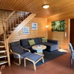 Wohnzimmer mit Sofa, Sessel und Treppe zu einer oberen Etage.