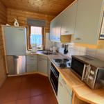 Küche mit Holzdecke, grauen Schränken und Edelstahlgeräten.