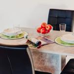 Esstisch mit vier Stühlen, Obstschale und Zeitungen.