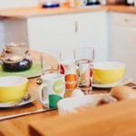 Esstisch mit Tassen, Tellern und einem Kerzenhalter.