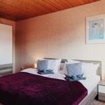 Schlafzimmer mit Bett, Nachttisch und Kleiderschrank. Holzdecke und Wandbild.