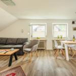 Wohn- und Essbereich mit Sofa, Tisch und Stühlen unter Dachschrägen.