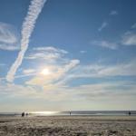 Strand mit Sonne und Wolken am Horizont