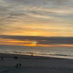 Sonnenuntergang am Strand mit wenigen Personen und dramatischem Himmel.