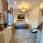 Schlafzimmer mit Bett, Decke, Lampe und Spiegel