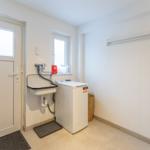 Waschraum mit Waschmaschine, Waschbecken und Fenster.