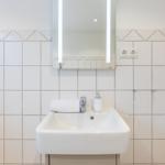 Badezimmer mit Waschbecken, Spiegel und Toilettenpapierhalter