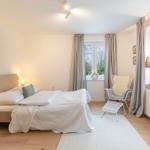 Schlafzimmer mit Bett, Stuhl und Fenstern.